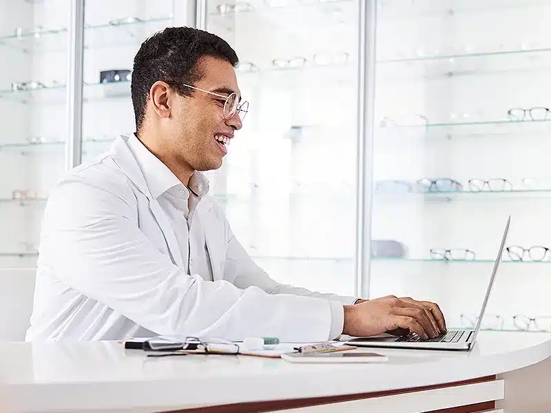 doctor looking at laptop with glasses display on wall