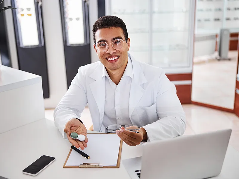 optometrist putting glasses on patient