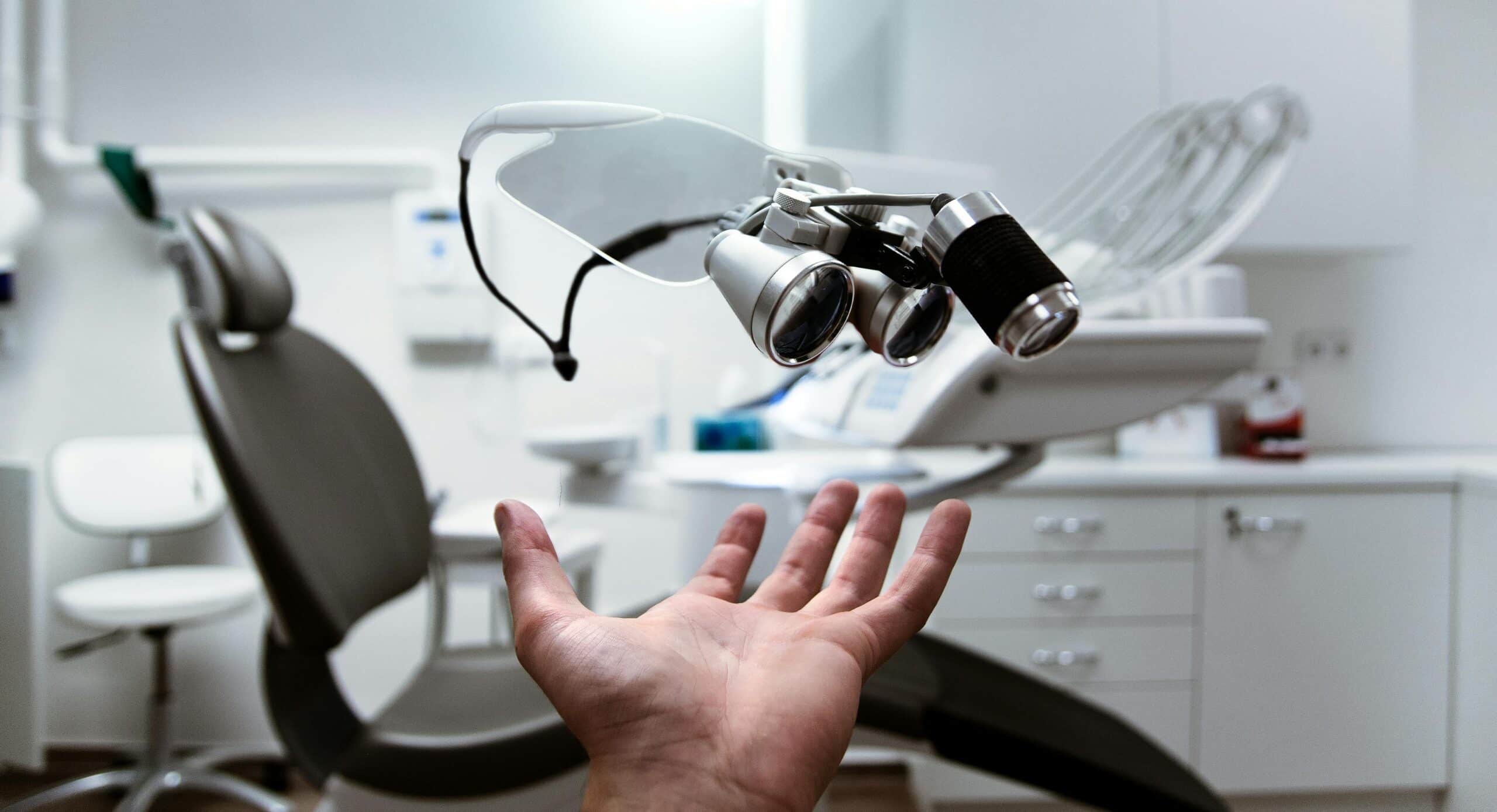 optometrist putting glasses on patient