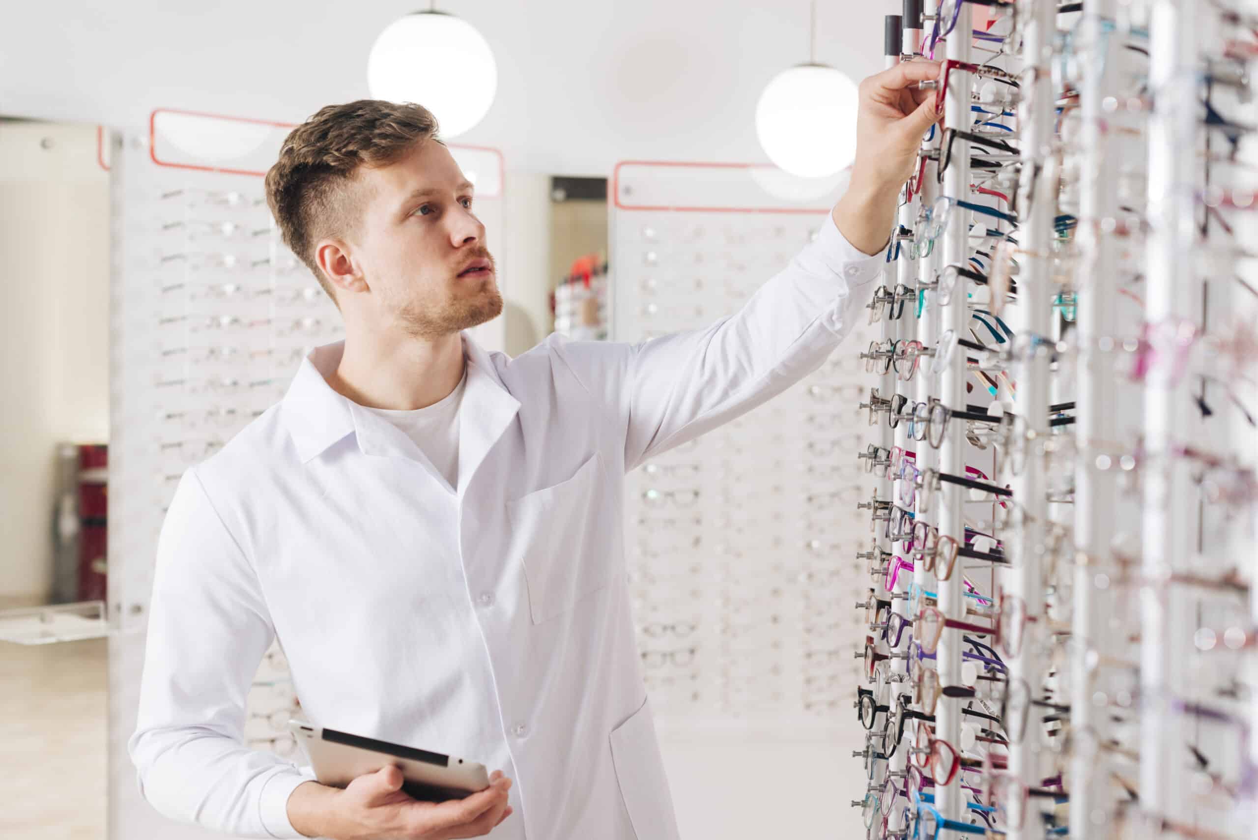 optometrist putting glasses on patient