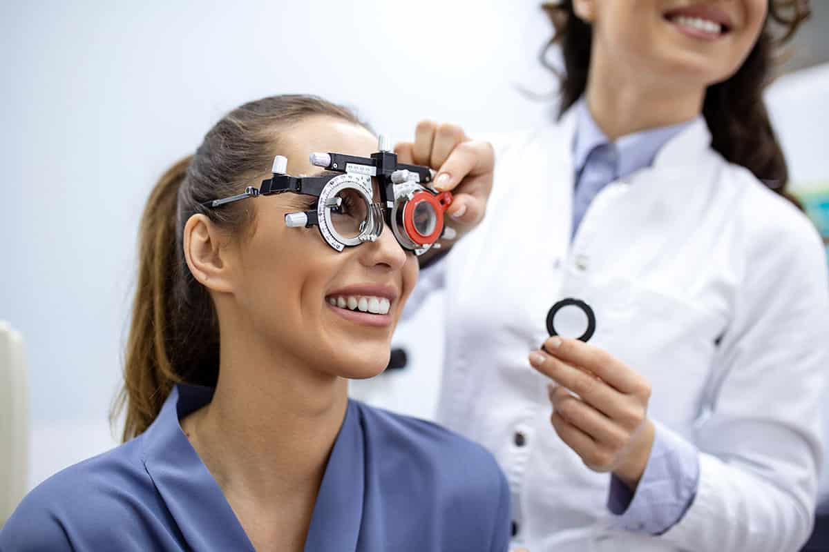 optometrist putting glasses on patient