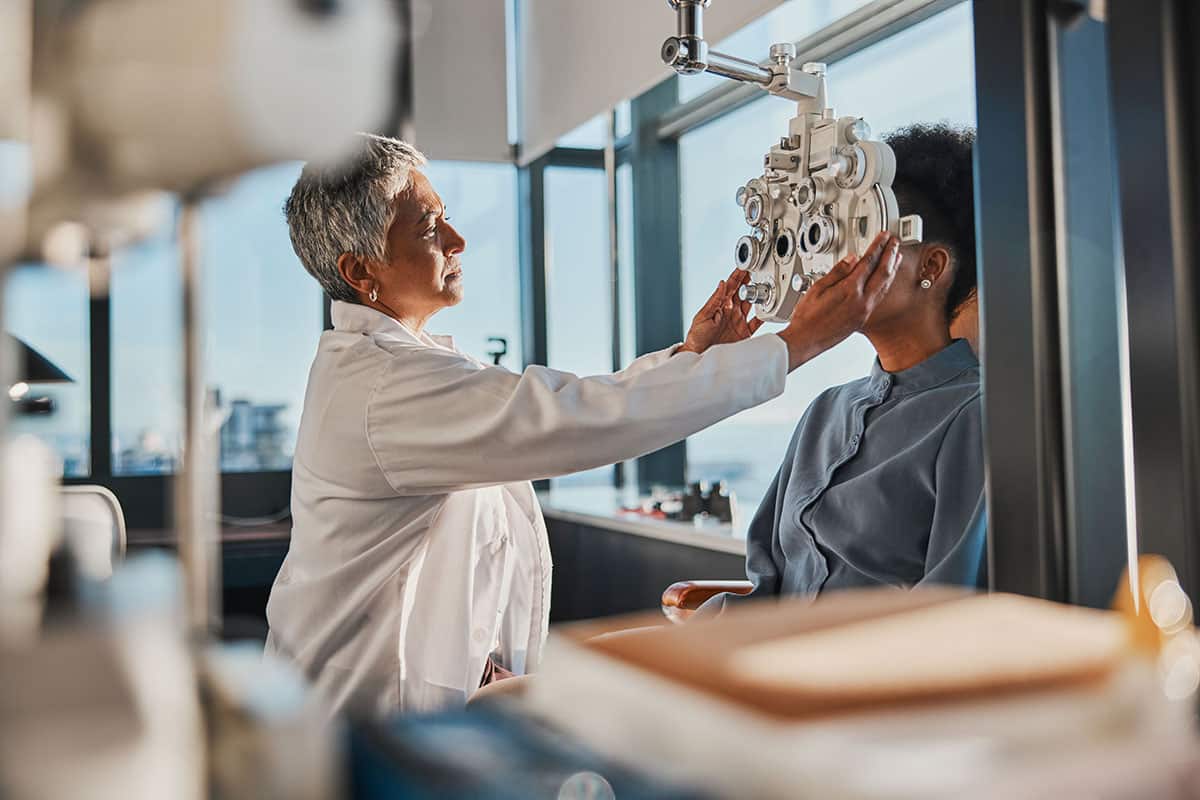 optometrist putting glasses on patient