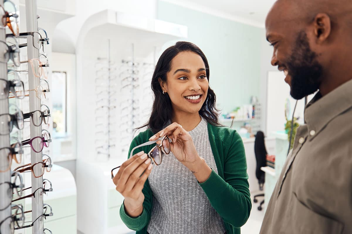 optometrist putting glasses on patient