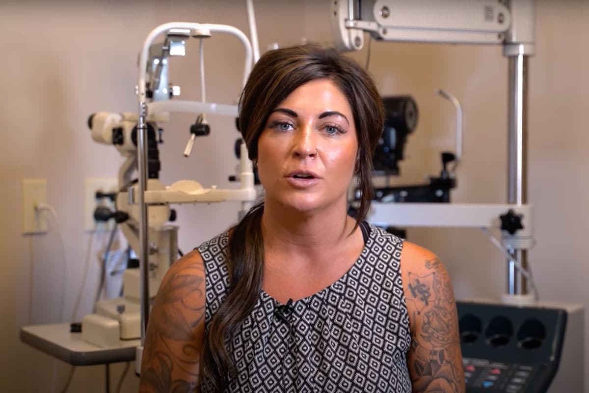 optometrist putting glasses on patient