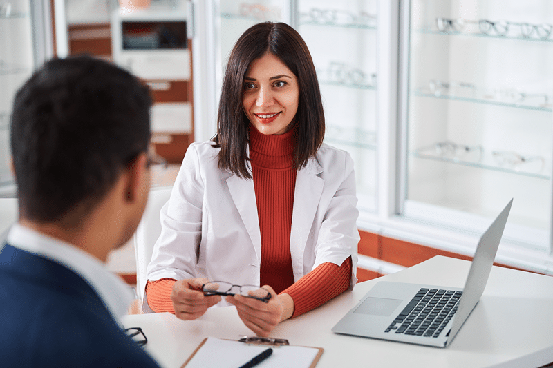 optometrist putting glasses on patient