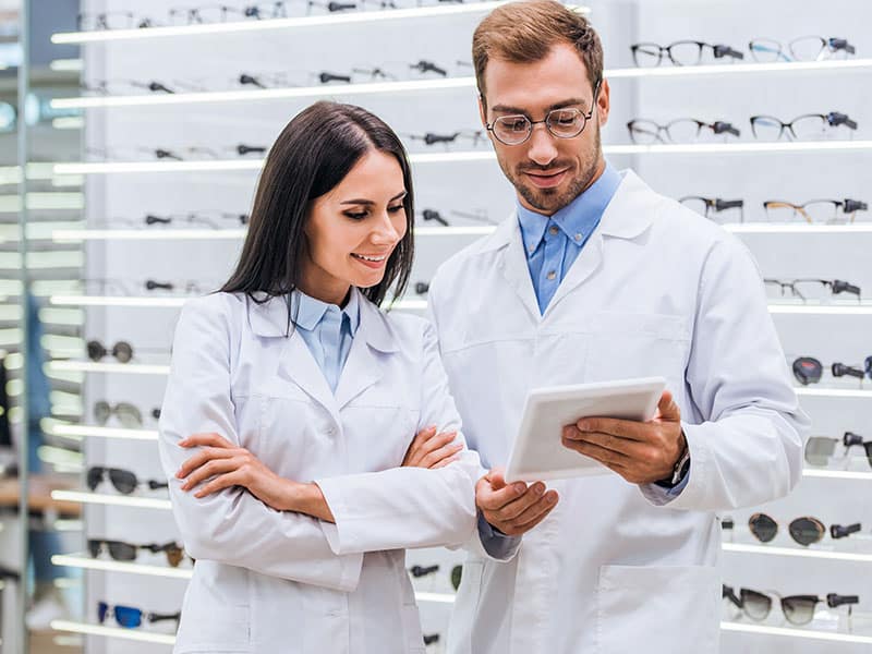 optometrist putting glasses on patient