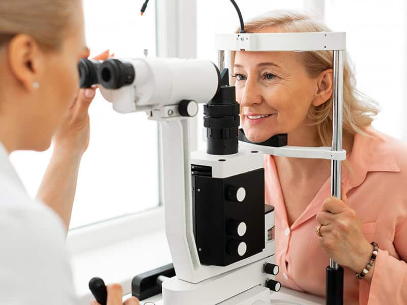 optometrist putting glasses on patient
