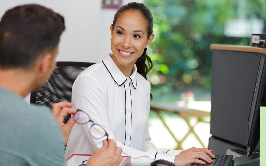 optician using computer while serving customer at her desk