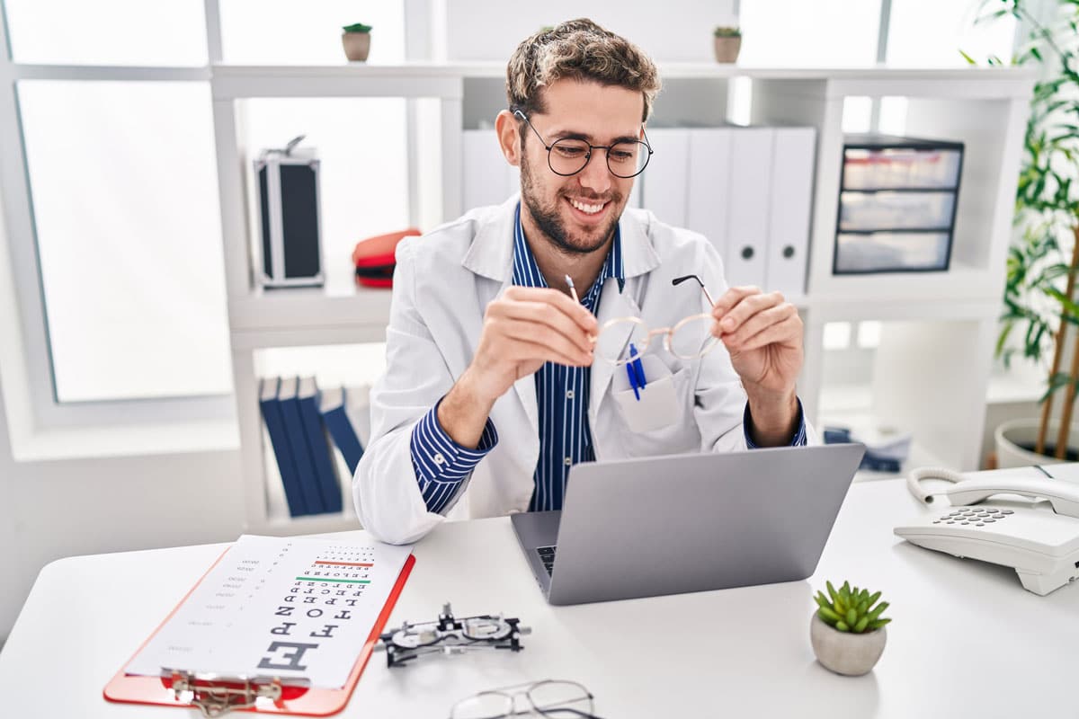 male optometrist at a laptop with glasses